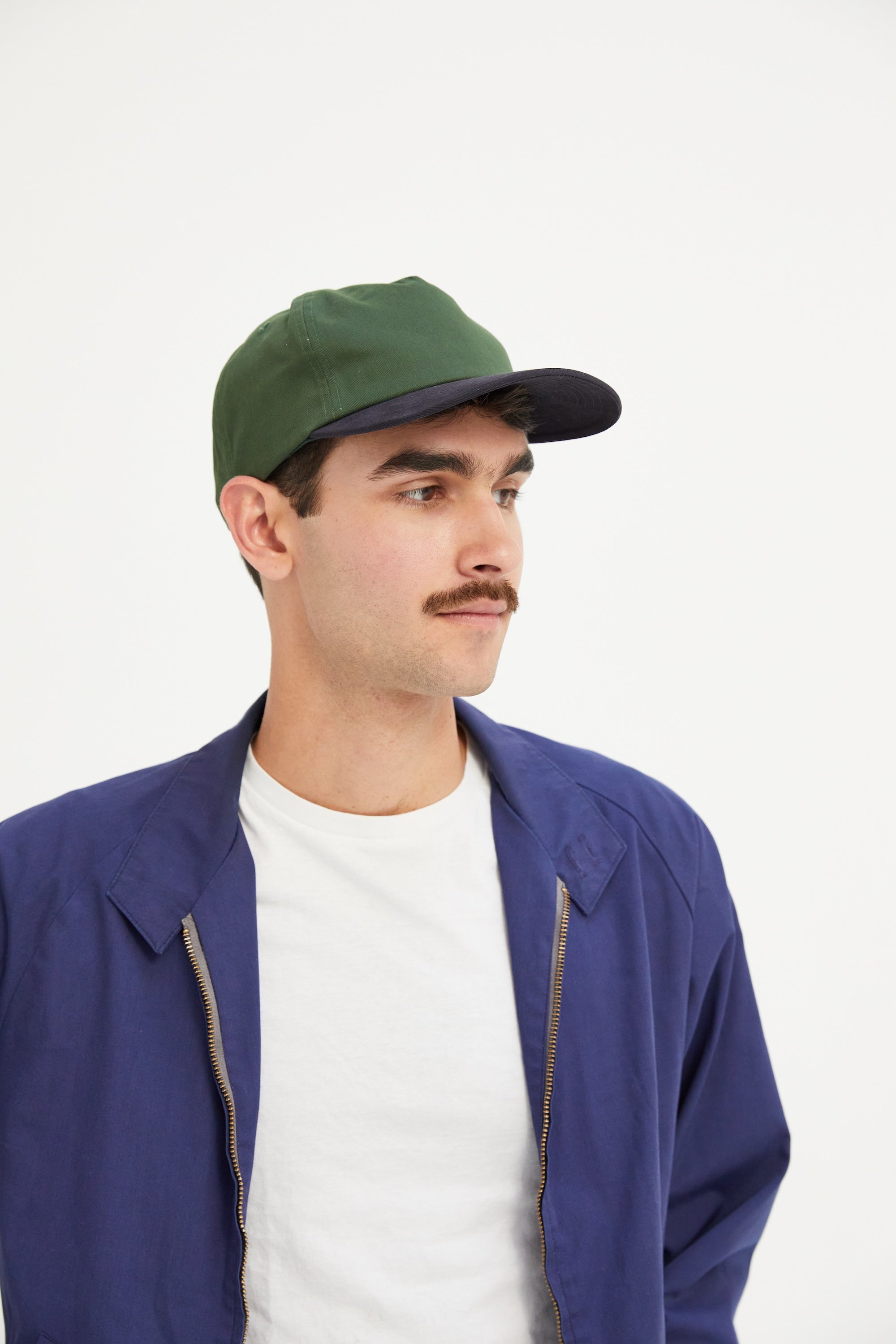 Side profile of a male model wearing a WELD MFG Two-Tone Brushed Cotton Twill Workhorse Snapback Hat with a slightly structured 5-panel crown and contrasting curved brim, Hunter Navy